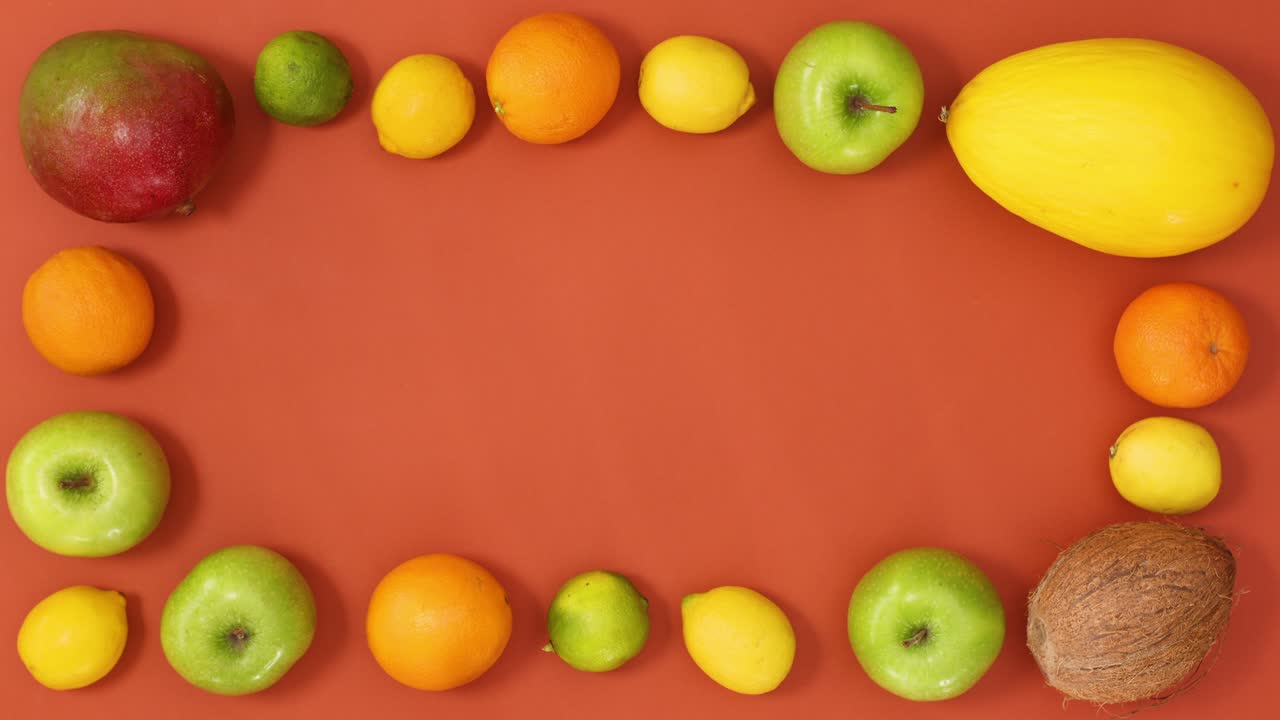 Tropic summer frame made of exotic fruits on orange background. Stop motion
