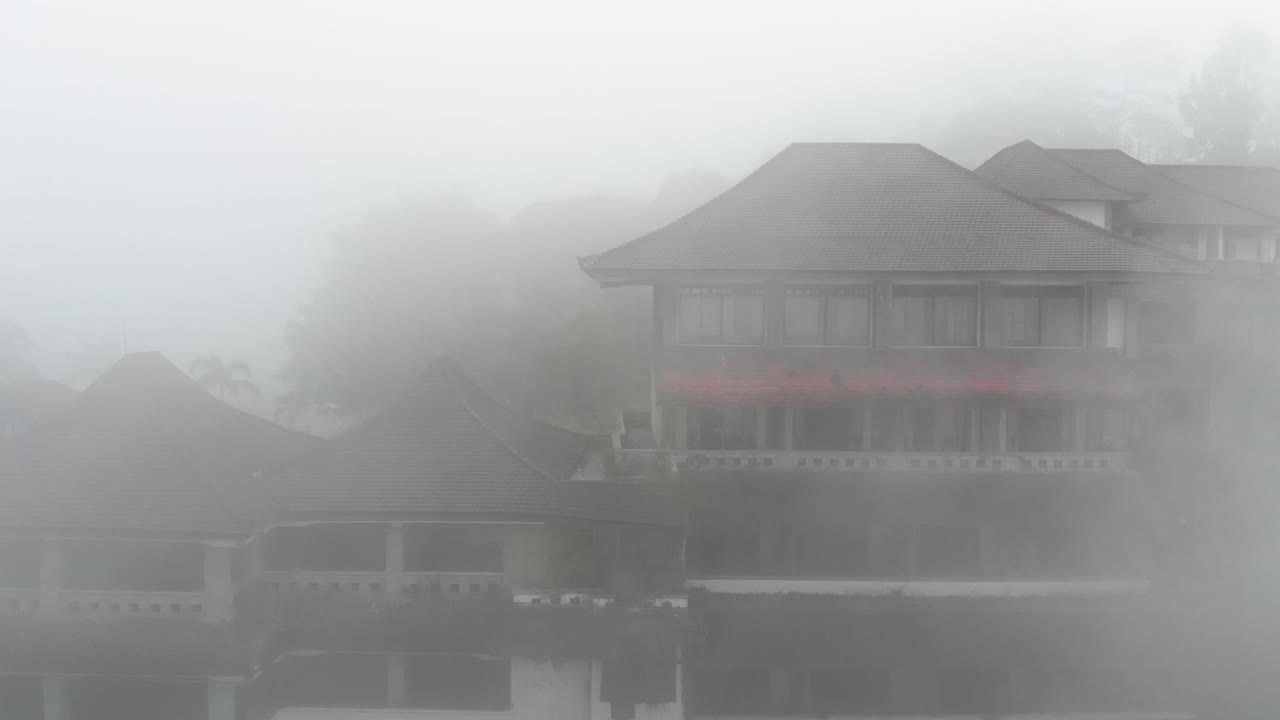 인도네시아 발리에 빨간 지붕이 있는 관광 리조트 근처의 짙은 안개가 자욱한 대기 경관