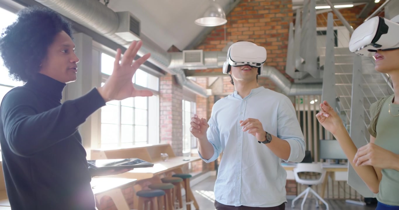 Istruttore che guida i tirocinanti tramite tablet, i tirocinanti pizzicano e indicano con visori VR bianchi per la dimostrazione.