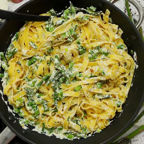 pasta tagliatelle casera con salsa cremosa de queso ricotta y espárragos frescos servidos en una sartén de hierro