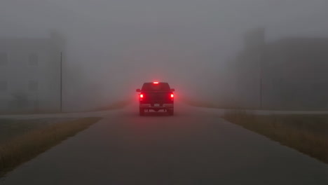 pickup truck driving in dense fog with brake lights on