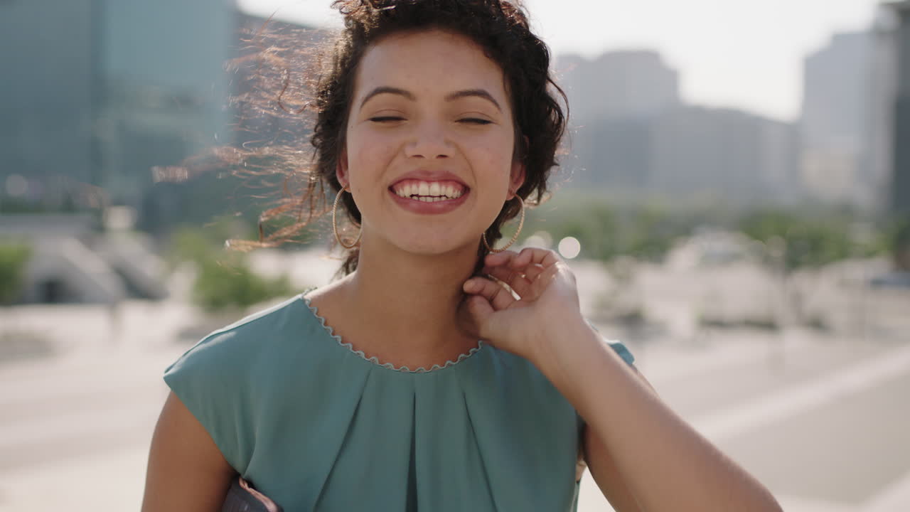 retrato de una hermosa joven mujer hispana sonriendo alegremente a la cámara con un elegante vestido azul disfrutando de una ciudad urbana soleada