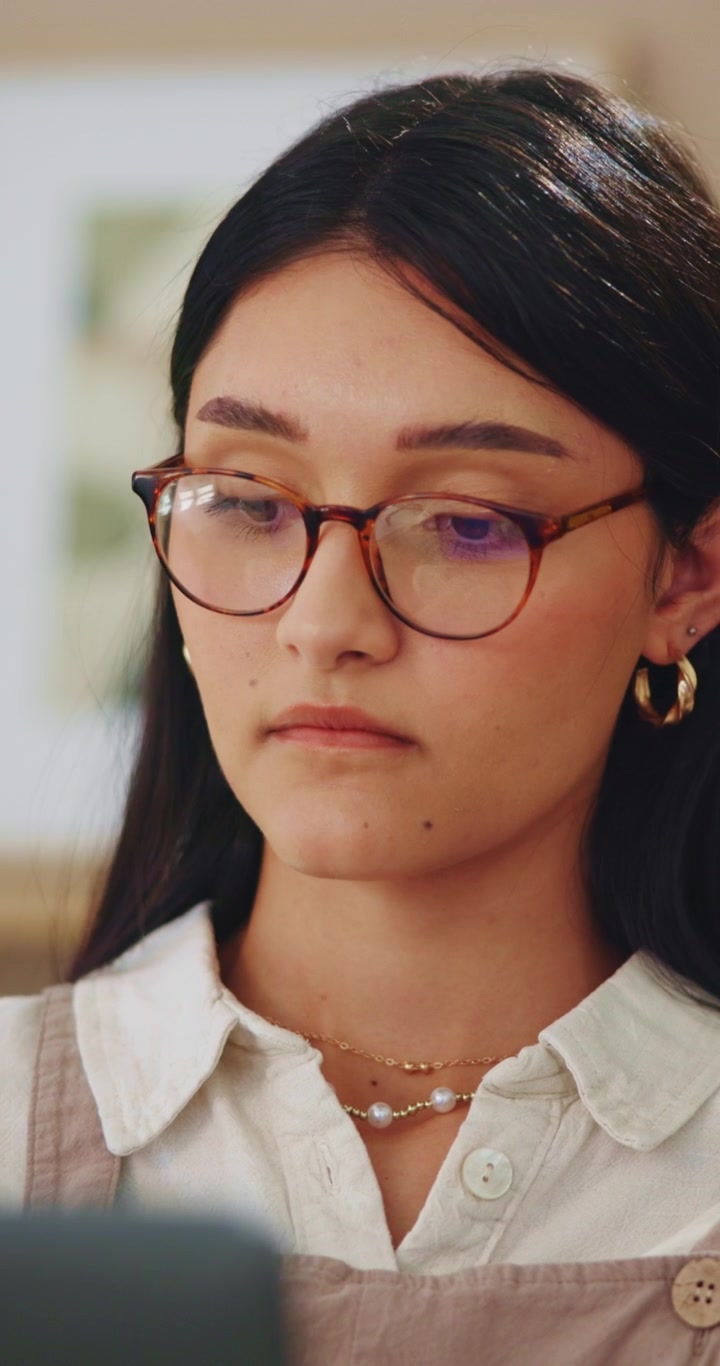 Giovane donna con gli occhiali che guarda lo schermo del portatile