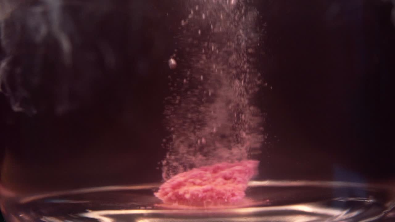 Slowmotion shot of efervescent pill dissolving in water. Bubbles going up. Stable shot with the Sony a7iii