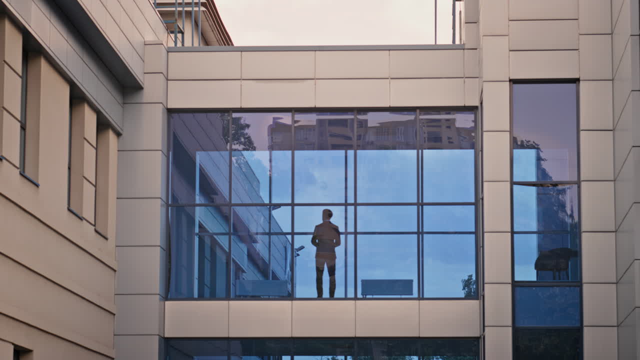 Contemplative businessman standing window modern office overlooking city skyline
