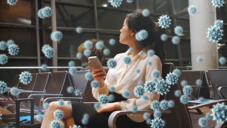 animation of floating macro covid-19 cells over mixed race woman using smartphone at airport