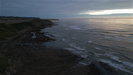 establishing aerial drone shot of cleveland way cliffs in scarborough north yorkshire on misty morning at sunrise