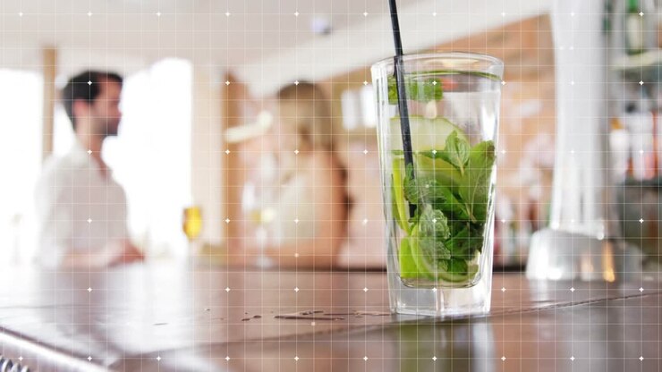 bartender's hand reaching mojito glass on cocktail bar counter, lifting it off for clearing space