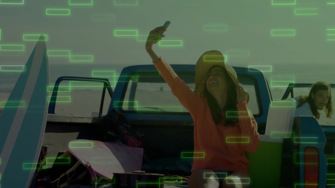 Woman taking selfie at beach with digital data animation overlay