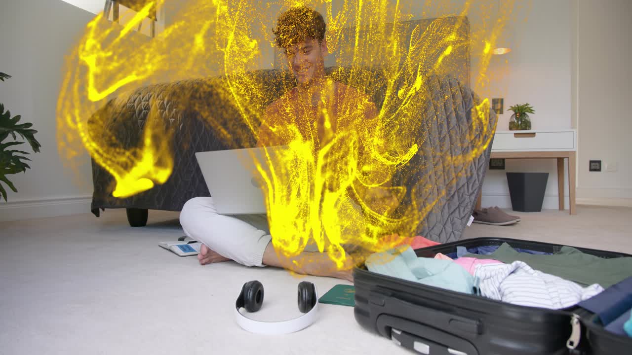 Man tapping smartphone while using laptop crosslegged planning travel yellow ribbons wrapping scene