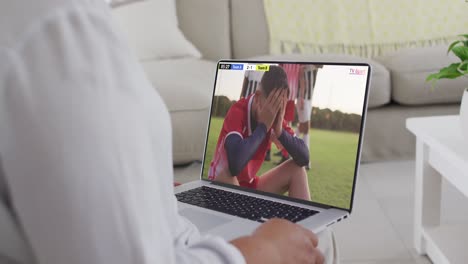 Video-Einer-Person,-Die-Auf-Der-Couch-Sitzt-Und-Sich-Ein-Fußballspiel-Auf-Dem-Laptop-Ansieht