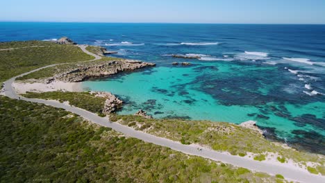 Aerial-view-of-cyclists-riding,-in-Salmon-Bay,-Rottnest-Island,-Australia--forward,-drone-shot