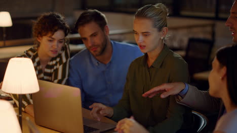 Young-girl-saying-goodbye-to-team-in-office.-People-analyzing-data-on-laptop.