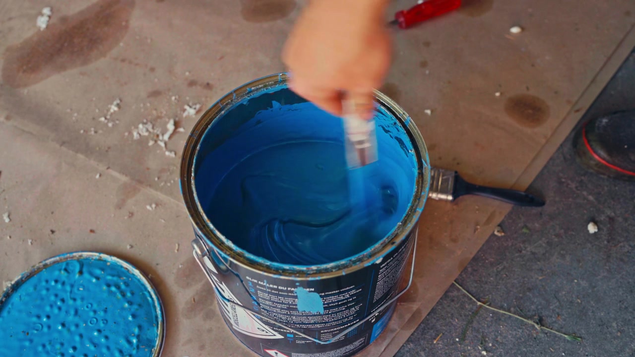 Miscelazione manuale di vernice blu in un secchio - Primo piano