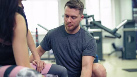 fitness, sport, exercising and weightlifting concept - young woman and personal trainer with dumbbells flexing muscles in gym