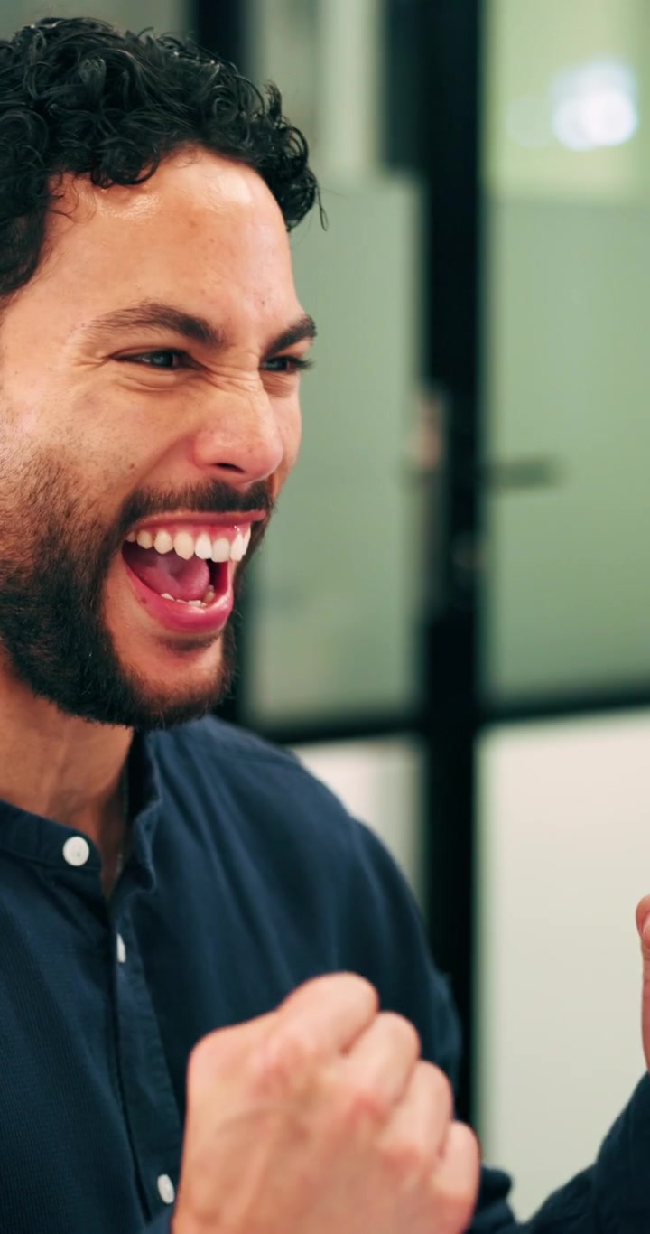 Giovane uomo che ride e festeggia il successo in ufficio
