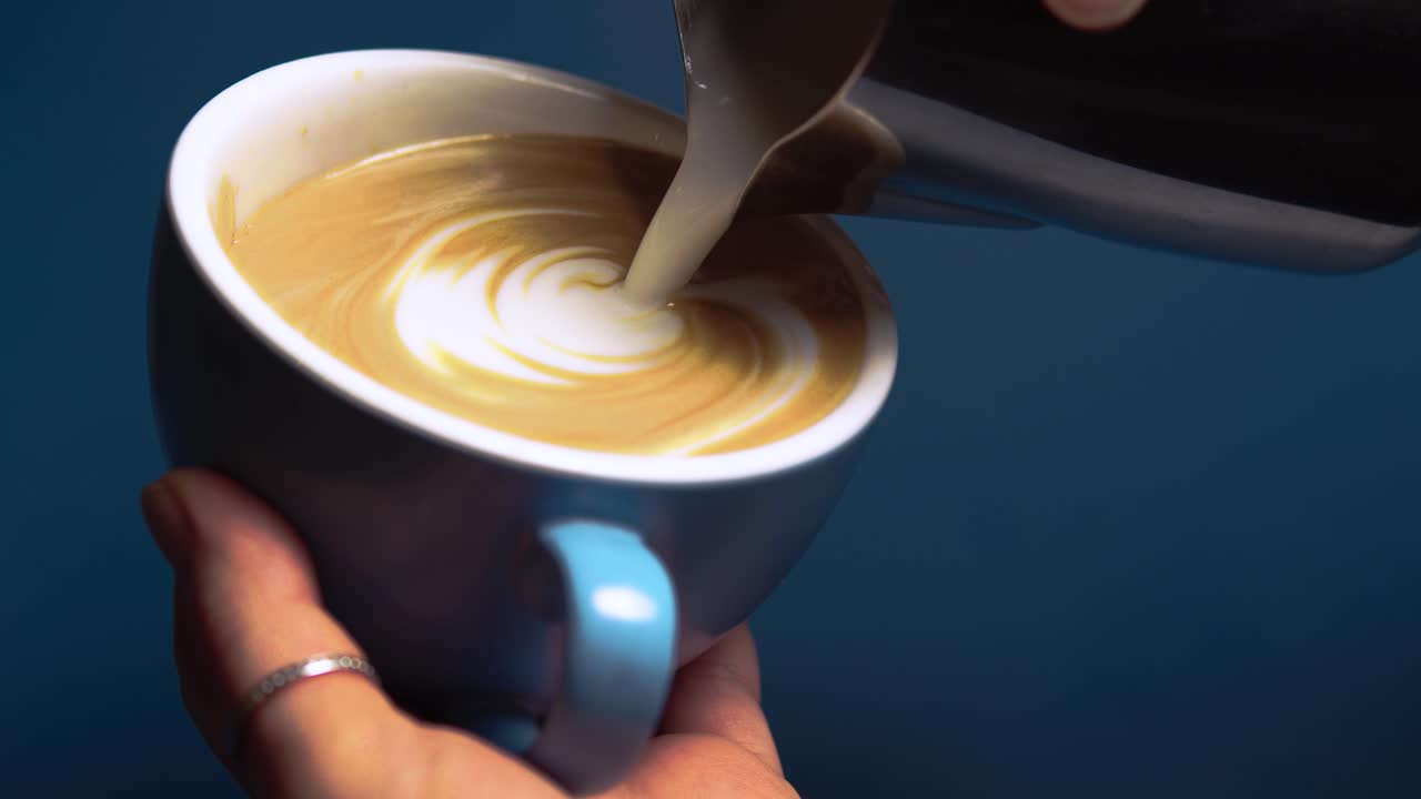Smooth coffee pour into a blue cafe cup