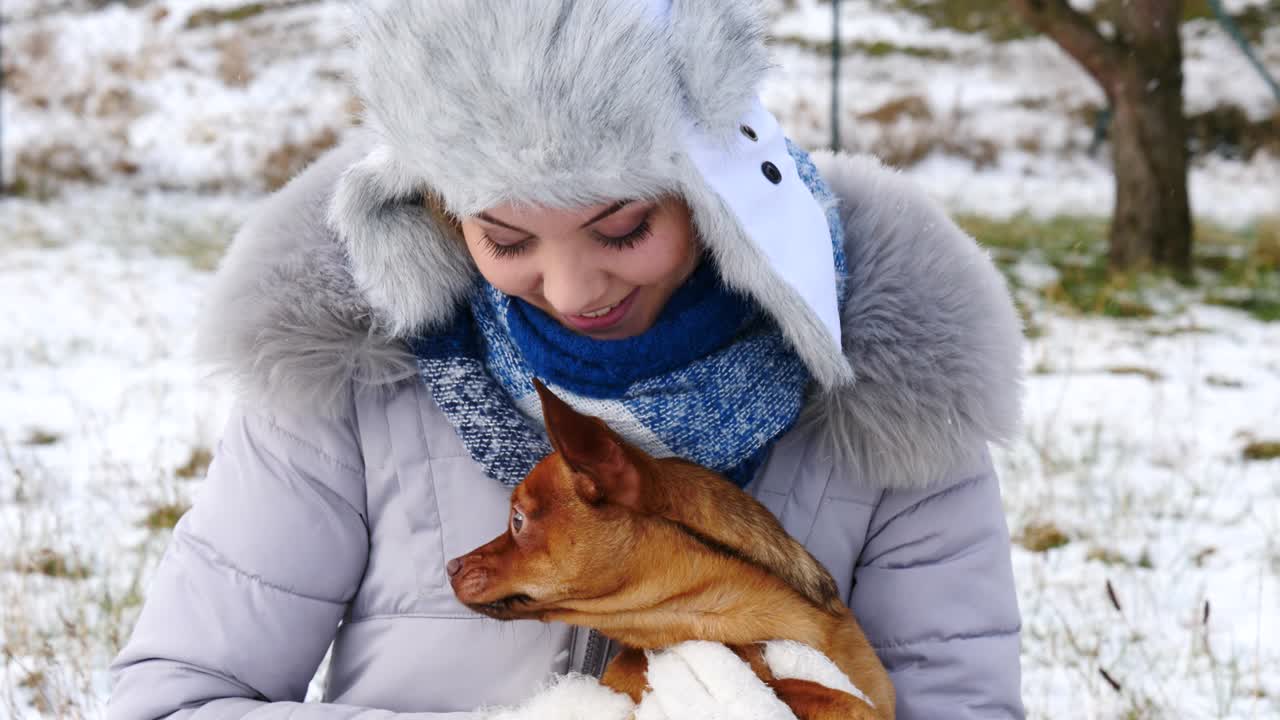 여자 는 겨울 밖 에서 작은 개 와 함께 놀고 있다