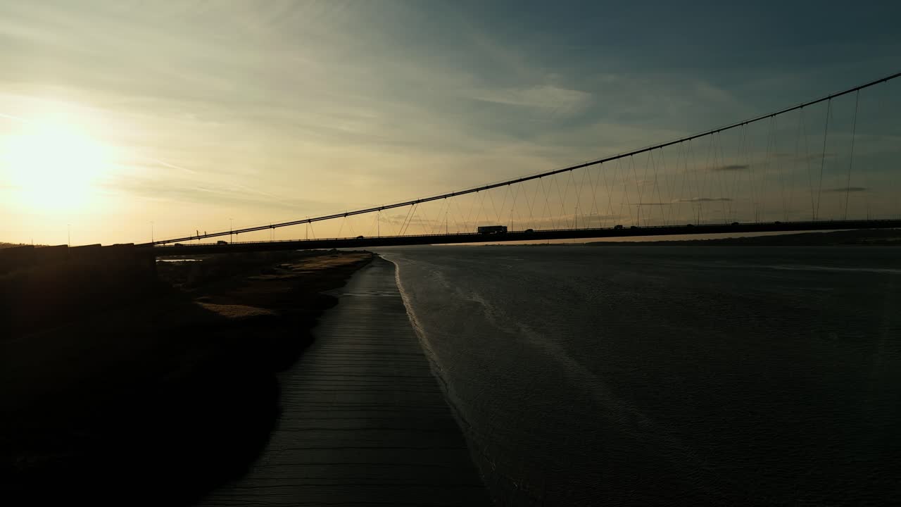 Humber Bridge bathed in sunset's warmth, cars traverse its length