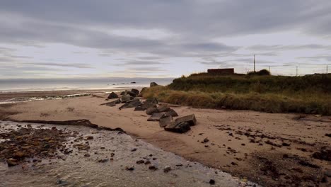 tiel burn fluye hacia el fiordo de adelante a través de la playa de kirkcaldy con bloques de hormigón antitanque de ww2 en la otra orilla