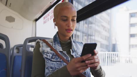 mixed race woman taking the bus and using her phone