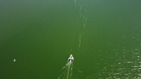 Aerial-follow-shot-of-a-boat-on-lake-Sihlsee-moving-towards-a-long-bridge-with-mountain-range-behind