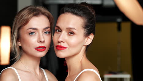 two women with red lipstick in studio setting