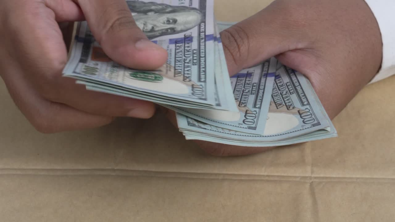 Close Up of hands holding and counting stack of hundres dollar US bills cash financial transaction concept 4K video