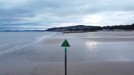 coastal tide marker aerial view low descending pull back across moody overcast low tide seaside beach