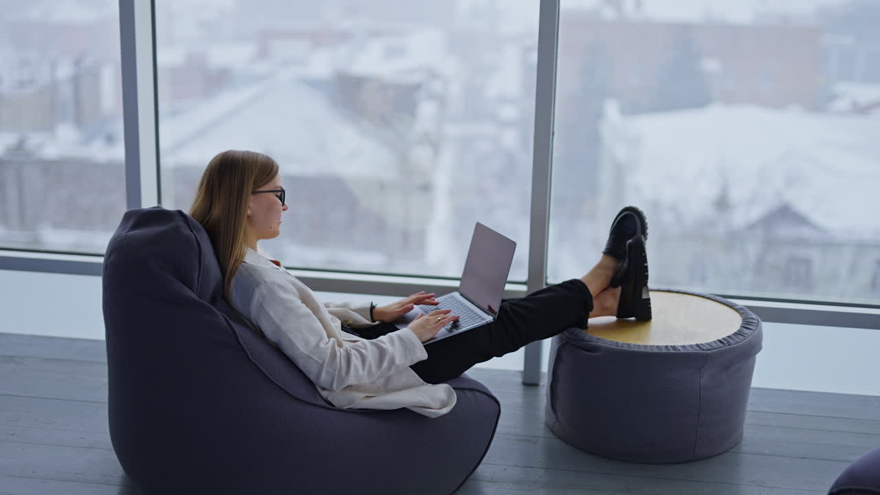 Woman Working on Laptop in Bean Bag Chair with Snow View