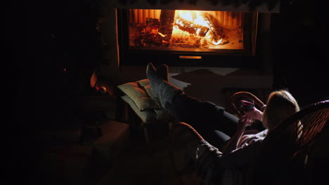 woman with a glass of wine is relaxing by the fireplace top view