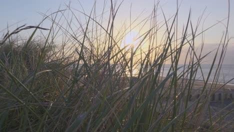 Hierba-De-La-Playa-Que-Sopla-En-El-Viento-En-Cámara-Lenta-Durante-La-Puesta-De-Sol-En-Fleetwood,-Lancashire,-Reino-Unido