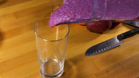 pouring fruit smoothie into glass from blender