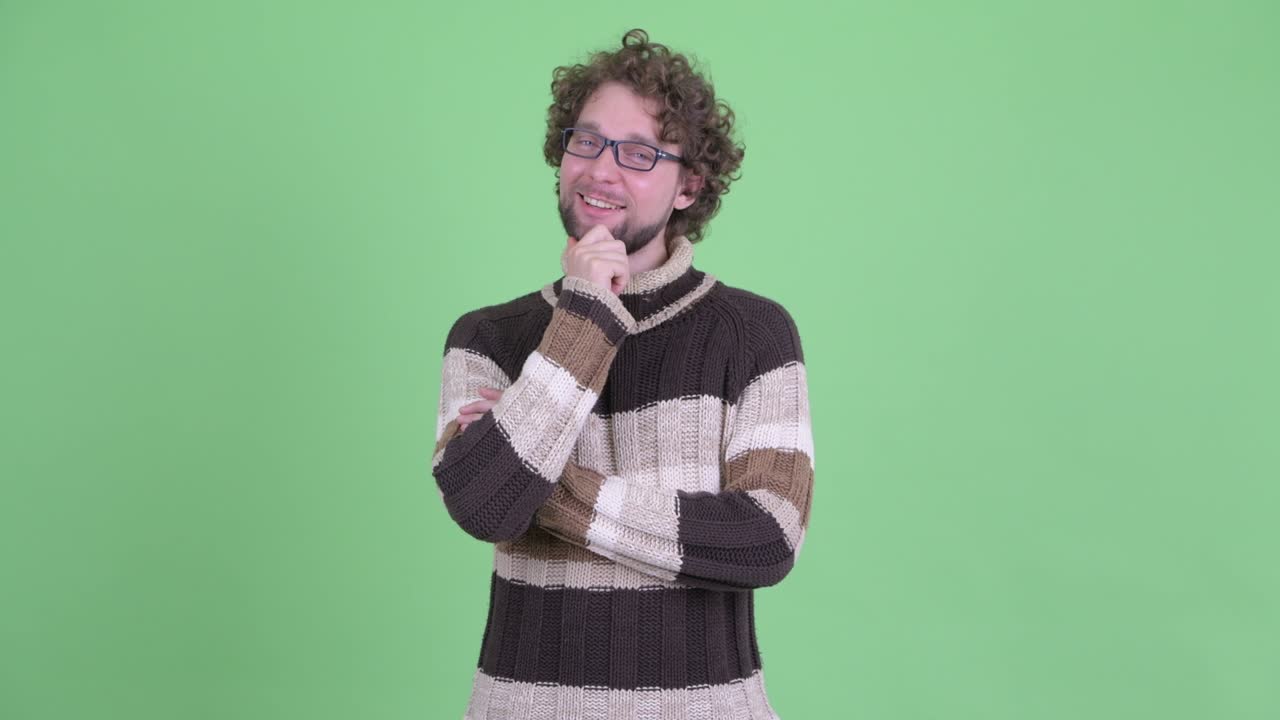 un joven guapo con barba y cabello rizado.