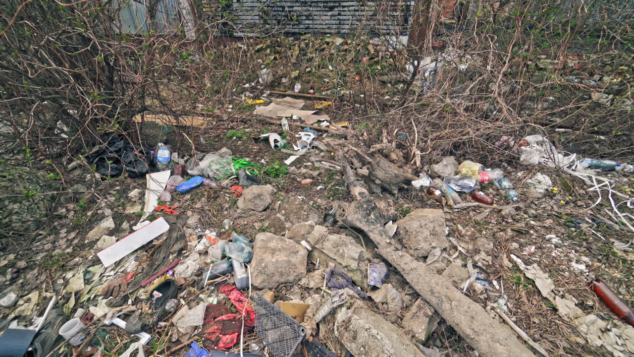 Different garbage lying on the ground in nature. A lot of plastic bottles, litter around the natural background. Pollution problem.