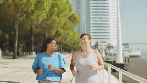 front view of women running along embankment and talking