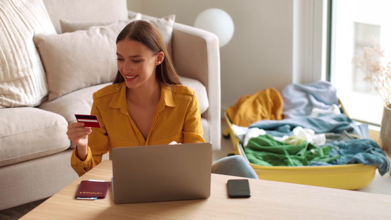 Giovane donna che prenota viaggi online con carta di credito e laptop