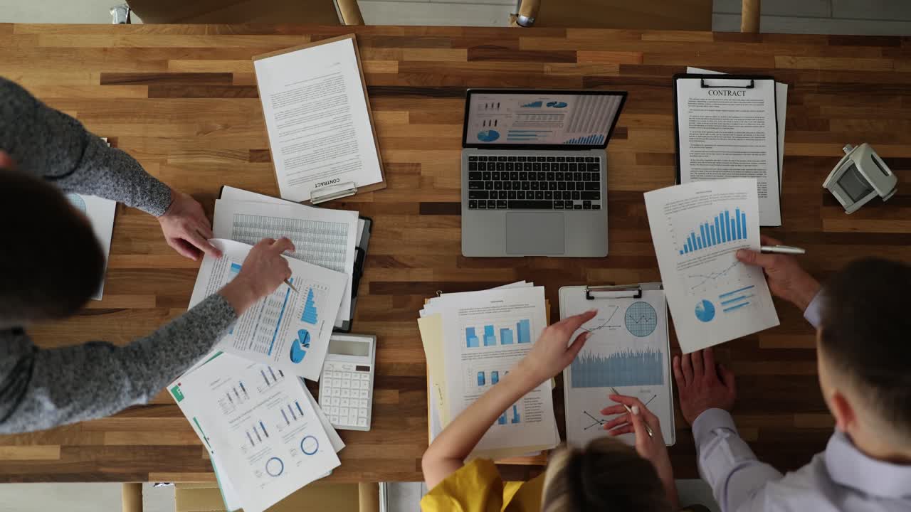 Employees team examine investigation papers at wooden desk