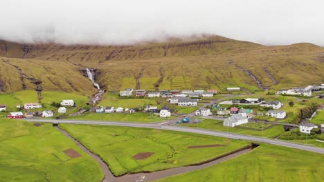 aerial over small village with waterfall at the faroe islands