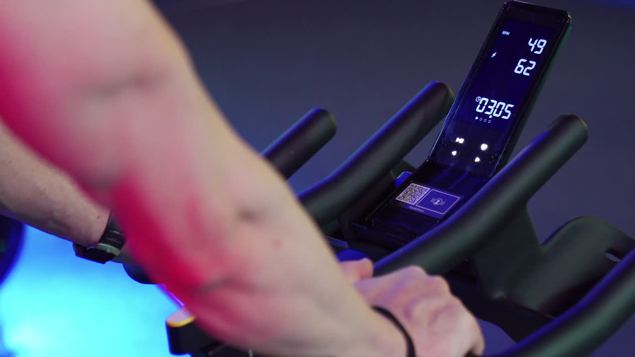 Cardio training on stationary bike. Close up of man exercising legs doing cardio workout cycling bikes