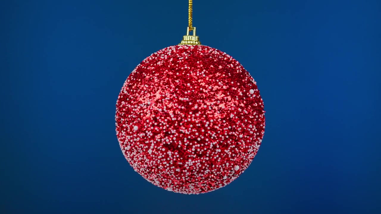 Roter Glitzer-Weihnachtsbaumschmuck hängt vor blauem Hintergrund