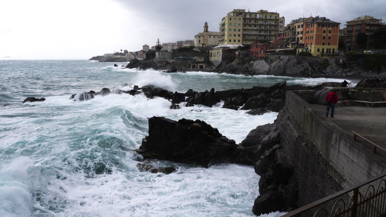 Ondata che si infrange sulla costa rocciosa e sulla diga vicino alla città di Genova, Italia