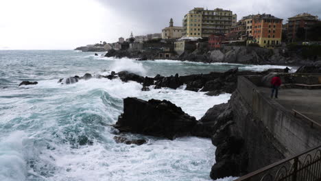 swell hitting rocky coast and seawall near city of genoa, italy