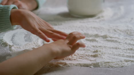 close up view of hands of two unrecognizable primary school children drawing on floured surface when cooking in kitchen