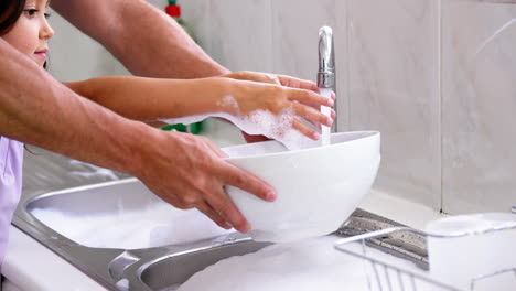 Close-up-father-and-daughter-doing-the-dishes-