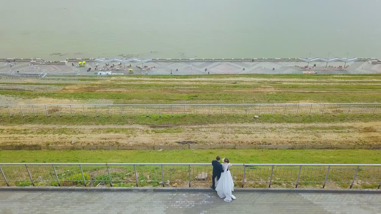 신혼 부부가 강변에서 강을 바라보고 있습니다.