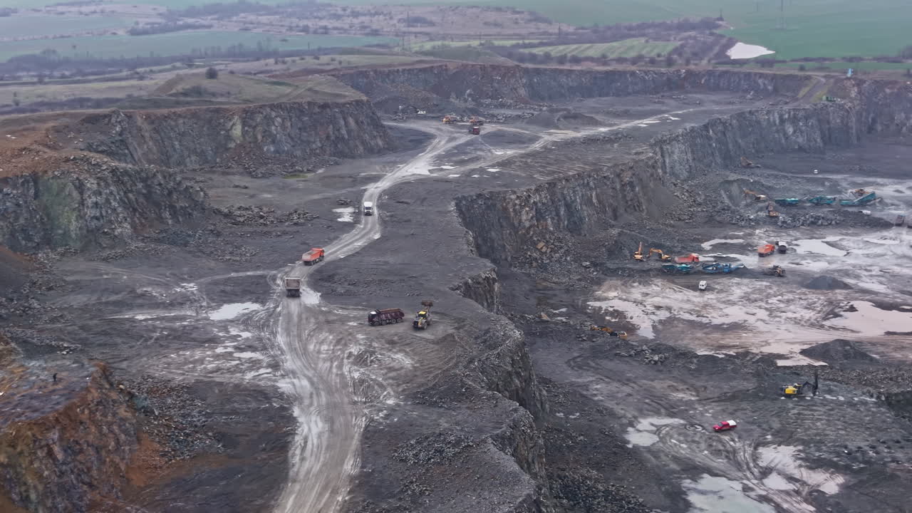 Granite quarry operation showing natural stone extraction process in an open pit area during daytime with heavy machinery at work