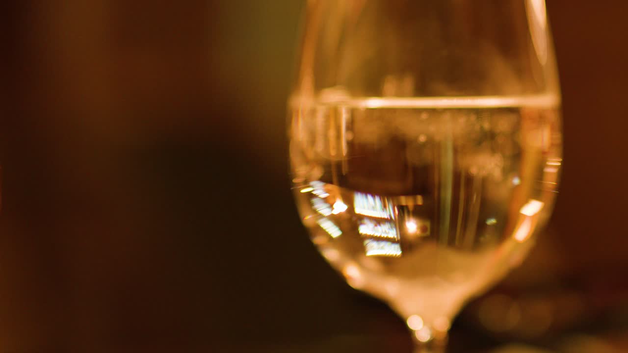 Calici da vino in una calda luce ambientale, mano che si allunga, elegante ambientazione da bar, profondità di campo ridotta