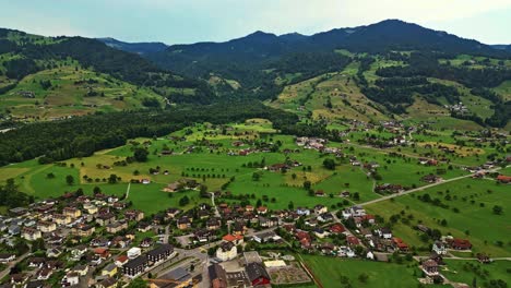 Aerial-view-of-a-picturesque-village-at-the-base-of-a-mountain,-surrounded-by-beautiful-greenery