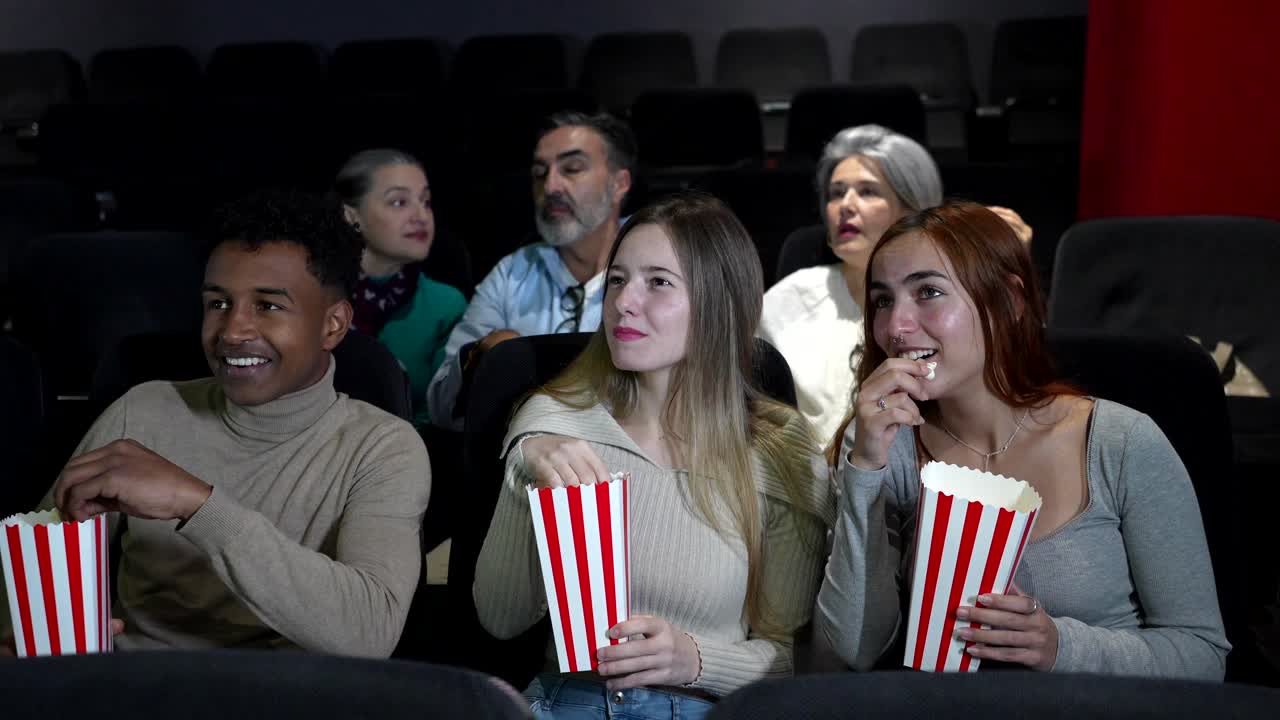 People enjoying a movie at the theater with popcorn